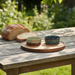 Loaf of bread and two ceramic bowls on a wooden table outdoors.