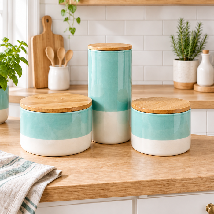 Three ceramic canisters with bamboo lids in a turquoise and white color scheme, arranged on a wooden kitchen counter with a white subway tile backsplash.